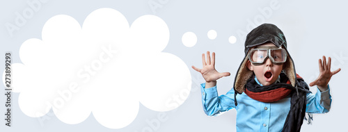 boy in a blue shirt, pilot's glasses, hat and scarf raised his hands on a light background