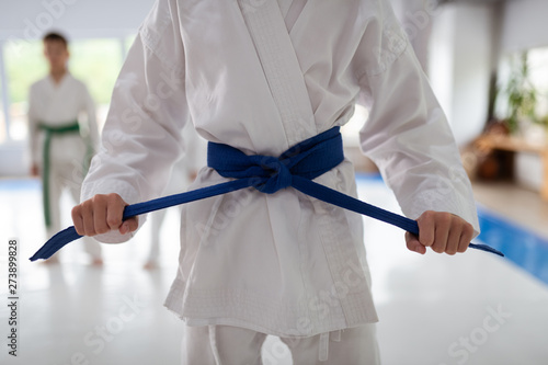 Close up of girl wearing white kimono tying her blue belt