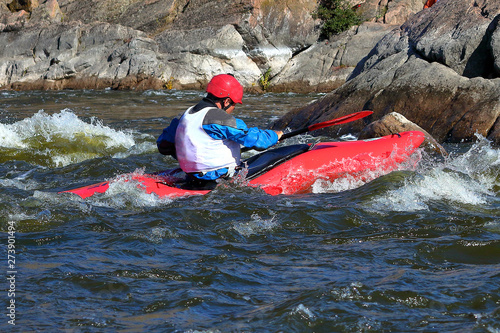 Whitewater kayaking on fast moving water of mountain river among the rapids, extreme water sport. Kayak freestyle on whitewater. Man in red kayak © watcherfox