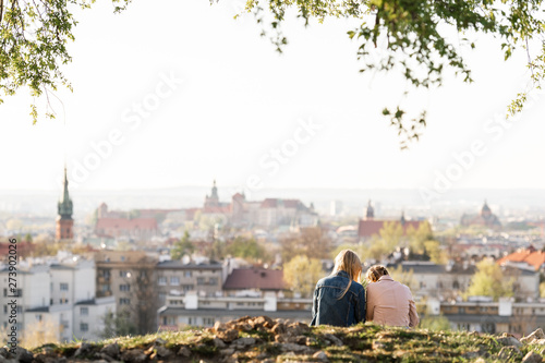 Female couple from behind on Krakus mound with a view at Wawel castle on background. photo