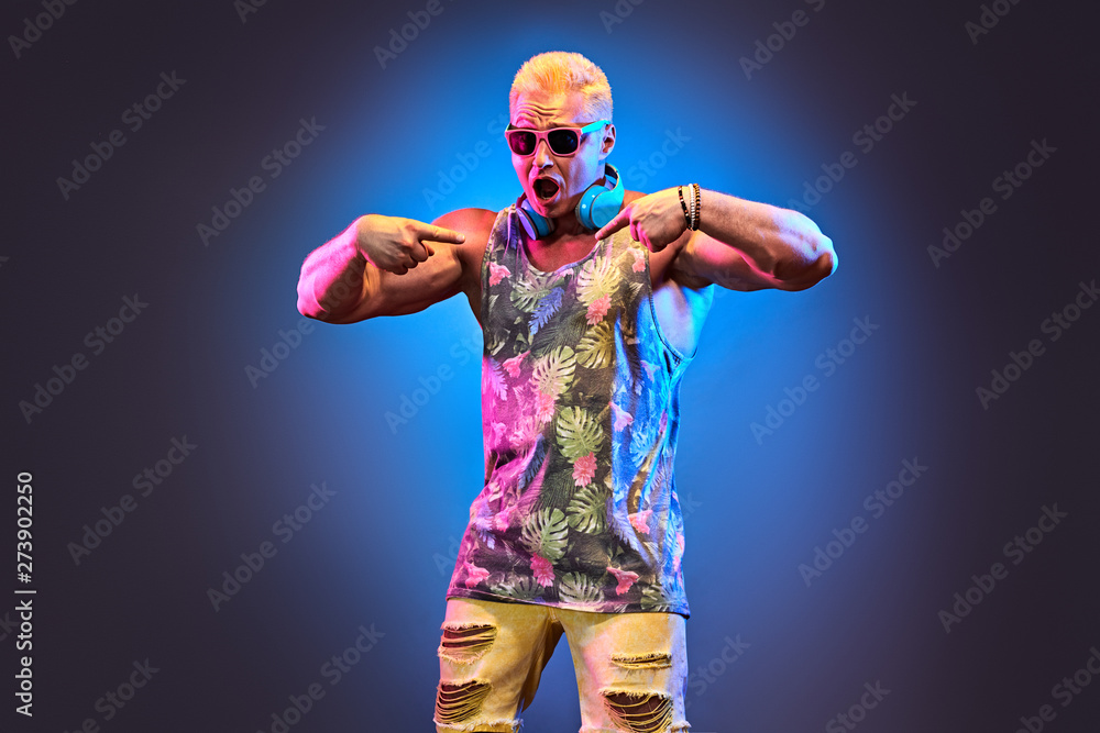 Fashion Excited DJ man dance with expression in neon light. Sexy emotional Handsome pumped-up blonde guy listen to music. Art neon fashionable style. Music festival nightclub, summer party concept Fashion Excited DJ man dance with expression in neon light. Sexy emotional Handsome pumped-up blonde guy listen to music. Art neon fashionable style. Music festival nightclub, summer party concept