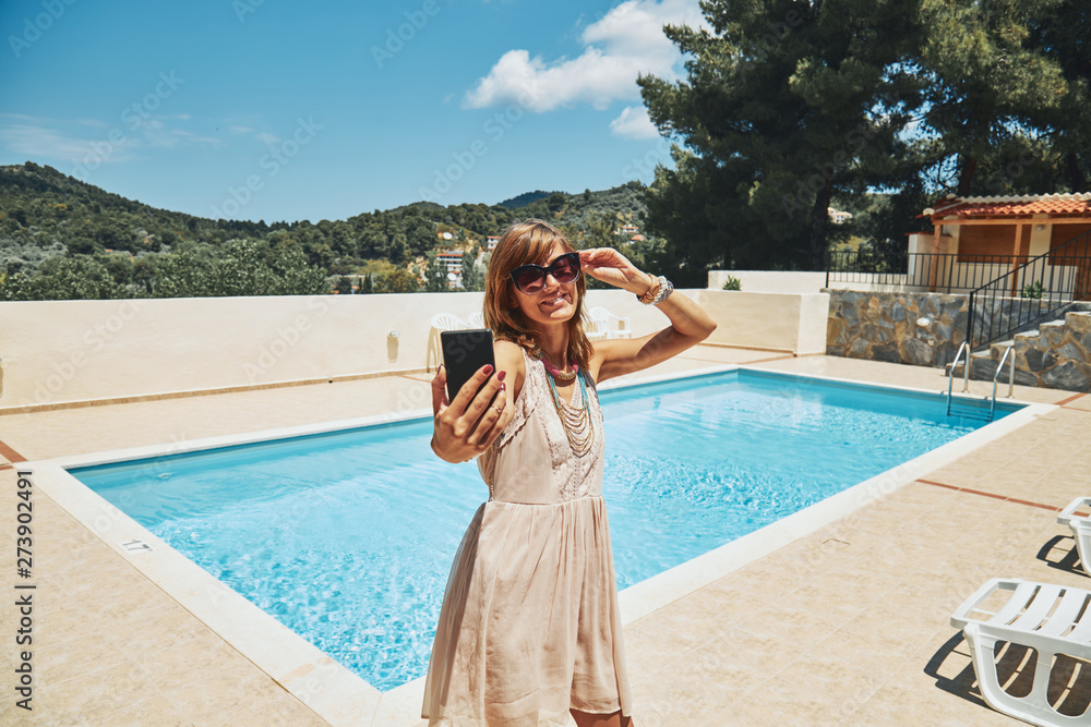 Cute young woman using cellphone near the swimming pool. Cute young woman using cellphone near the swimming pool.