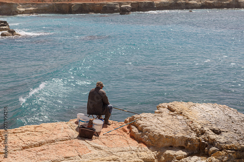 Man fishing at the sea rocky shore in Cyprus