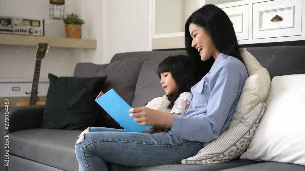 Family concept. Mother and daughter are reading books together in the living room. Family concept. Mother and daughter are reading books together in the living room.