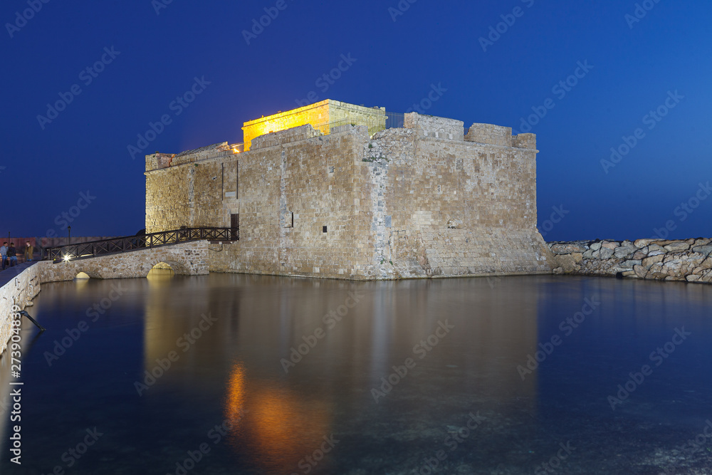 Illuminated Paphos Castle located in the city harbour at night with reflection in the water, Cyprus.