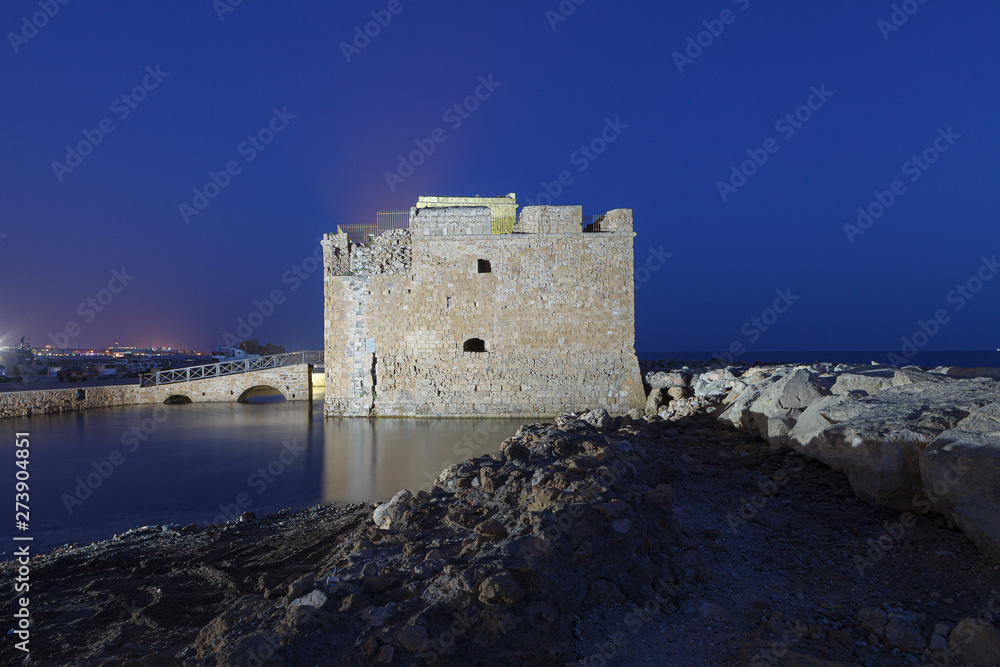 Illuminated Paphos Castle located in the city harbour at night with reflection in the water, Cyprus.