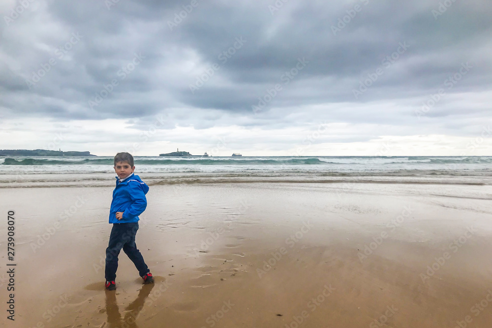 Little kid on the beach in a day with a stormy clous Little kid on the beach in a day with a stormy clous