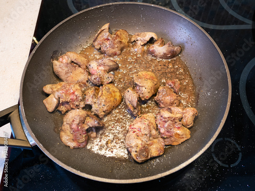 pieces of chicken liver are frying in pan