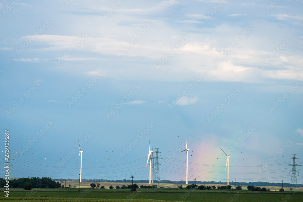 Wind warm on agricultural ground with cloudy sky and rainbow in background