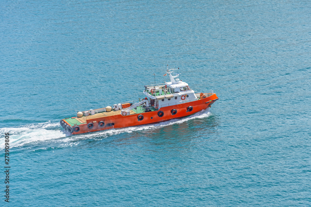Small tug ship sails in a harbor bay in the mediterranean sea. Small tug ship sails in a harbor bay in the mediterranean sea.