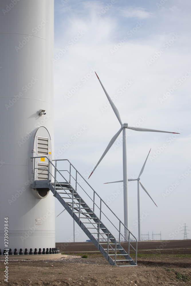 Close up of stairs and door of Wind turbine with two turbines in background Close up of stairs and door of Wind turbine with two turbines in background