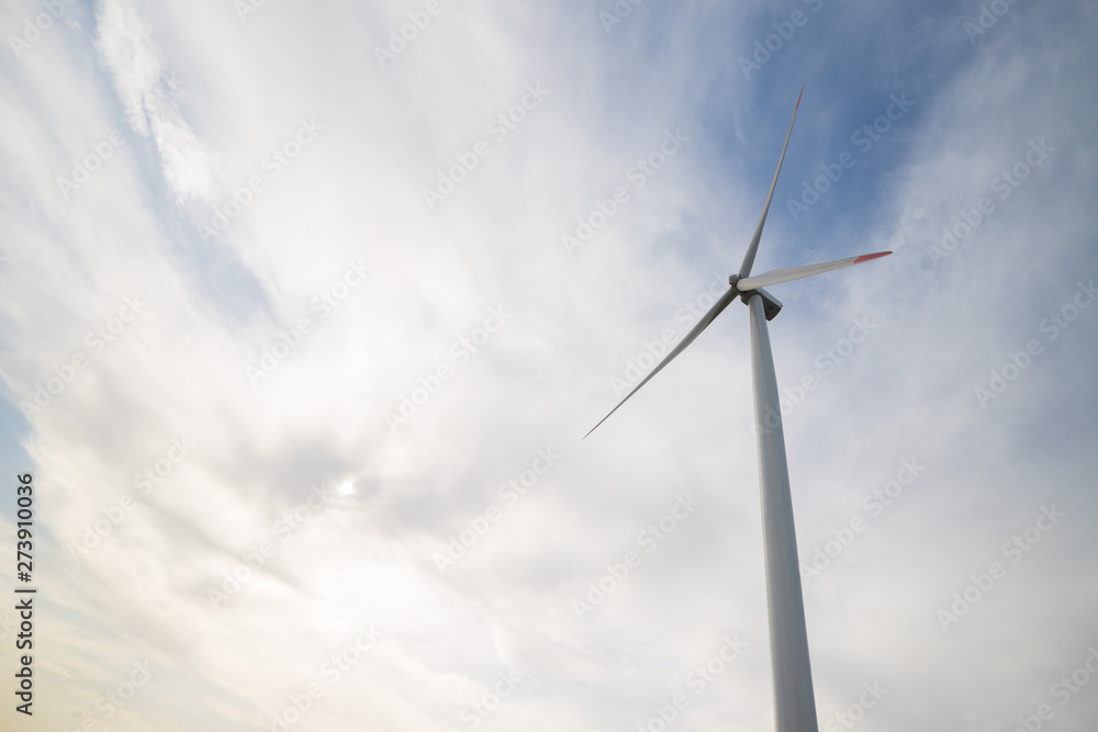 One wind turbine on agricultural ground with cloudy sky in background One wind turbine on agricultural ground with cloudy sky in background