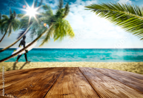 Desk of free space and blurred background of beach with surfer. Summer time and sunny day. 