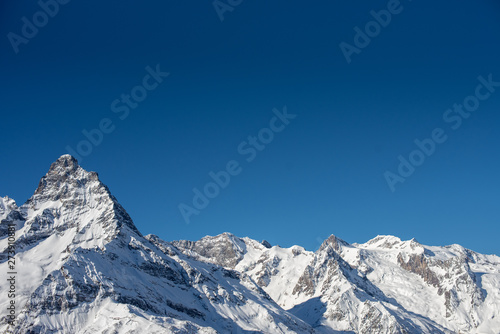 Winter mountains with snow and blue sky in nice sun day. Ski resort and sport concept. Caucasus Mountains  region Dombay. View from the top of Musa Achitara  copy space  moc up