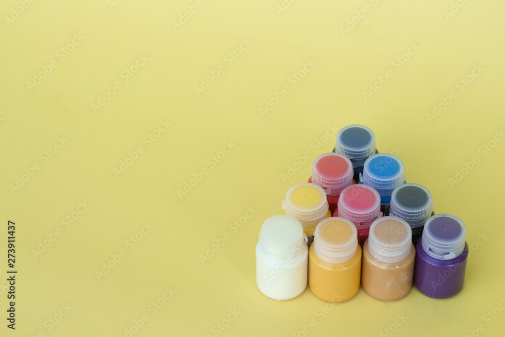 Multicolored plastic cans with acrylic paint on a yellow background. Art supplies. Set for the artist and for creativity. Multicolored plastic cans with acrylic paint on a yellow background. Art supplies. Set for the artist and for creativity.