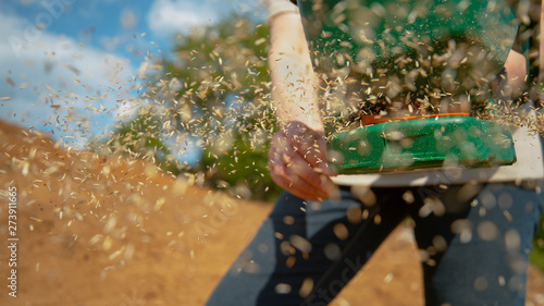 Foto CLOSE UP: Woman spinning a handle and sowing grass seeds across fertile land