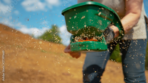 Obraz na plátně CLOSE UP: Farmer sowing grain in a fertile patch of soil on their large property