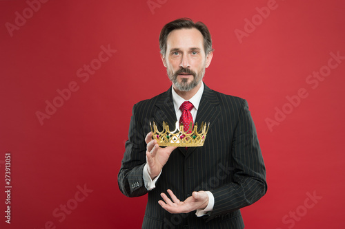 Reaching the height of luxury and elegance. Mature man holding luxury crown jewel on red background. Successful businessman with luxury and classy look. Luxury and prestige photo