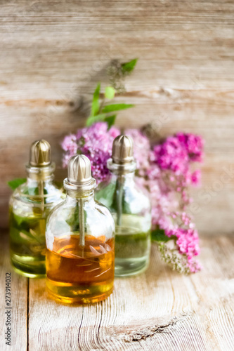 Spa perfume essential aroma oil glass bottles with flower blossoms on old wooden background