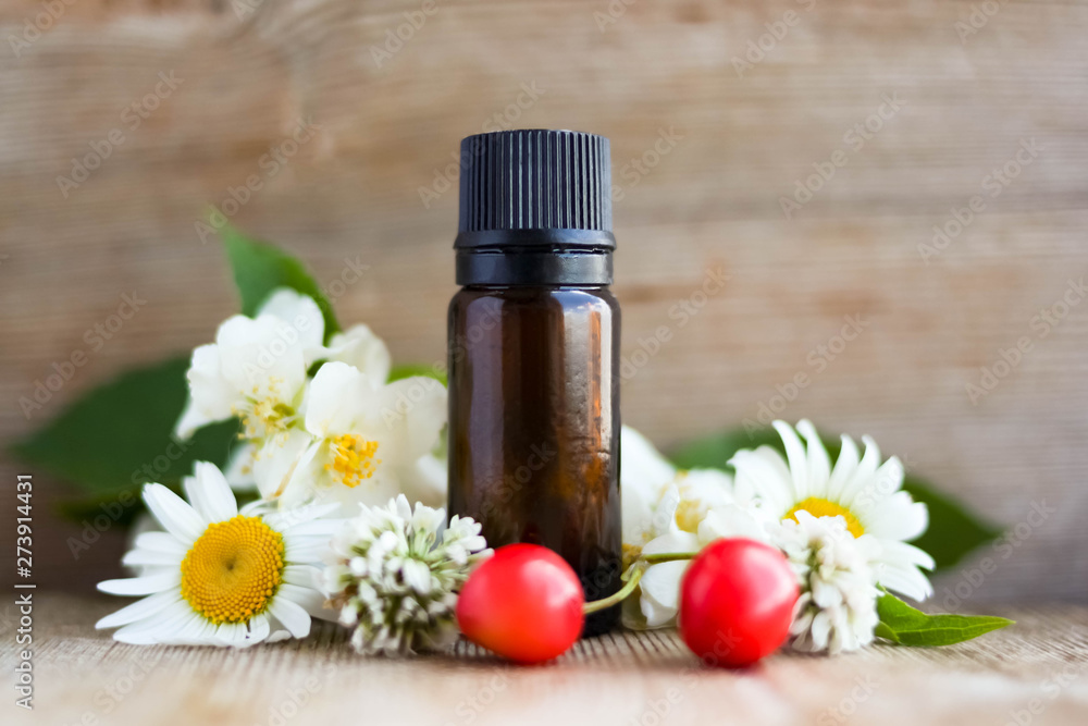 Spa perfume essential aroma oil glass bottle with flower blossoms on old wooden background Spa perfume essential aroma oil glass bottle with flower blossoms on old wooden background