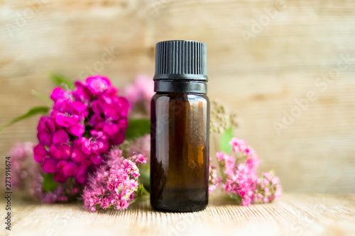 Spa perfume essential aroma oil glass bottle with flower blossoms on old wooden background