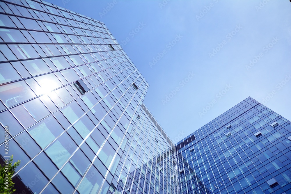 Bottom view of modern skyscrapers in business district against blue sky Bottom view of modern skyscrapers in business district against blue sky