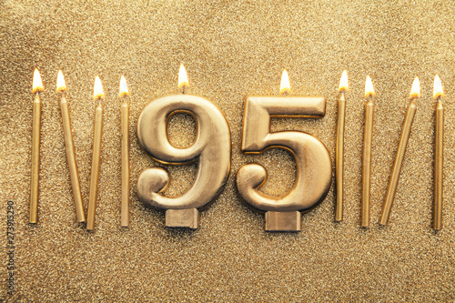 Number 95 gold celebration candle on a glitter background