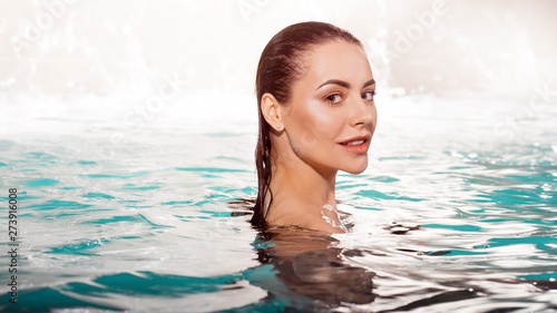 Smiling young beauty swims in the pool alone. Spa and relaxation, luxury hotel