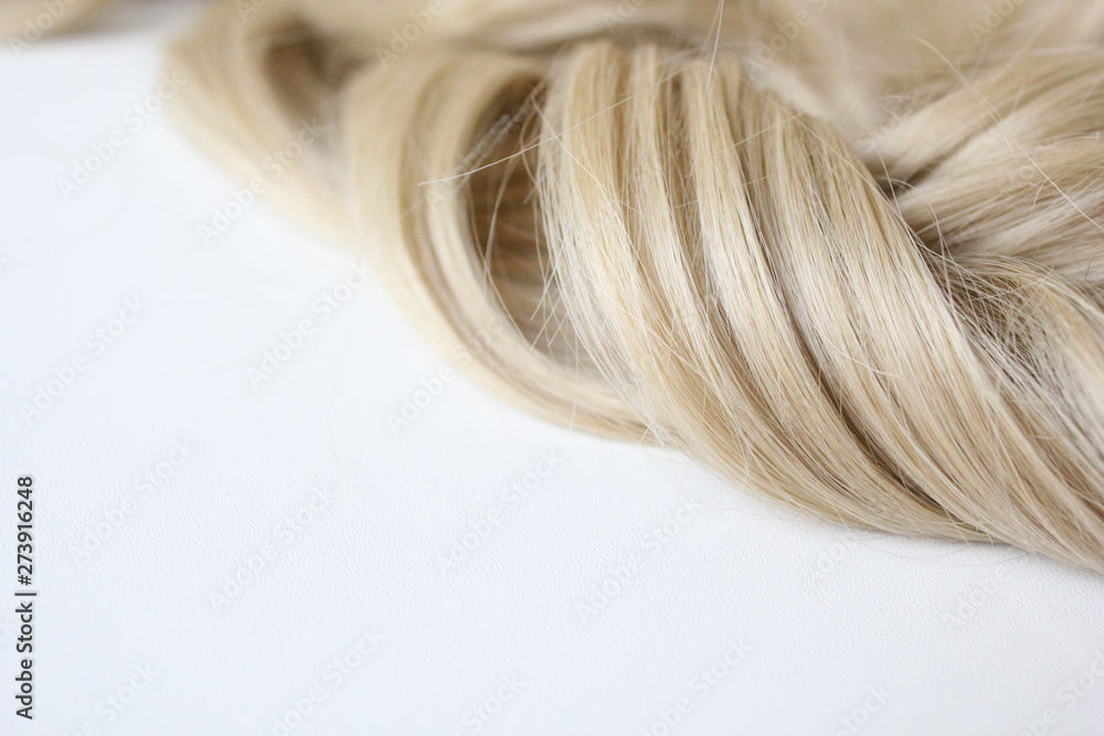 Naklejka premium Beautiful hair. Light hair. Curl. Strand of hair. Curl on white background. With free space for text. For a poster or business card.