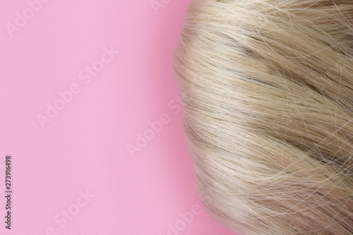 Beautiful hair. Light brown hair. Hair is gathered in a bun on a pink background. With free space for text. For a poster or business card.