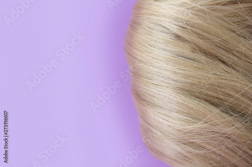 Beautiful hair. Light brown hair. Hair gathered in a bun on a lilac background. With free space for text. For a poster or business card.