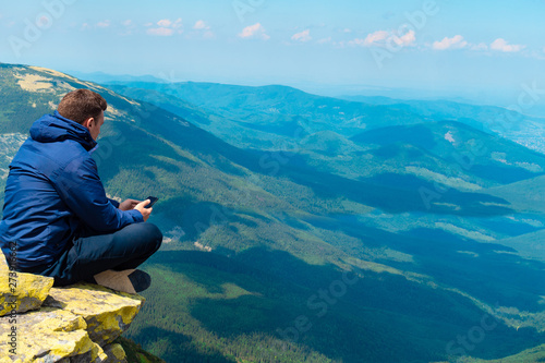 young guy makes a photo on the phone in the mountains