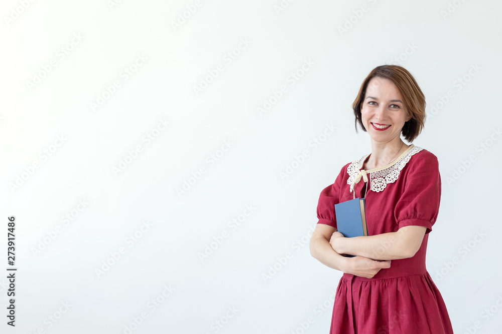 Portrait of cute smiling modest woman in dress holding classic book in hands on white background. Concept of lovers of history and classics. Copy space Portrait of cute smiling modest woman in dress holding classic book in hands on white background. Concept of lovers of history and classics. Copy space