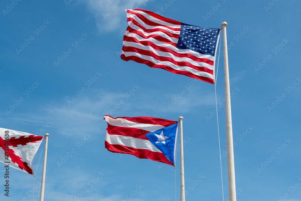 The flags of the United States, Puerto Rico and the Burgundy cross on a background of blue sky with clouds The flags of the United States, Puerto Rico and the Burgundy cross on a background of blue sky with clouds