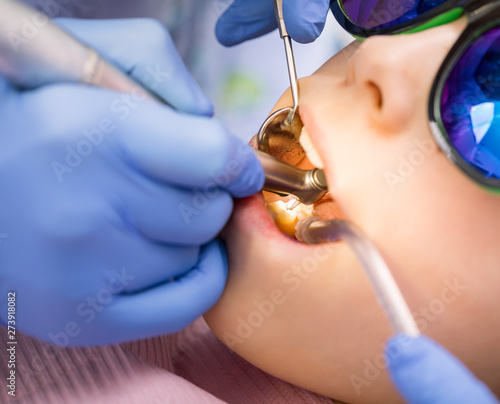 Preteen girl receiving dental filling procedure in pediatric dental clinic photo