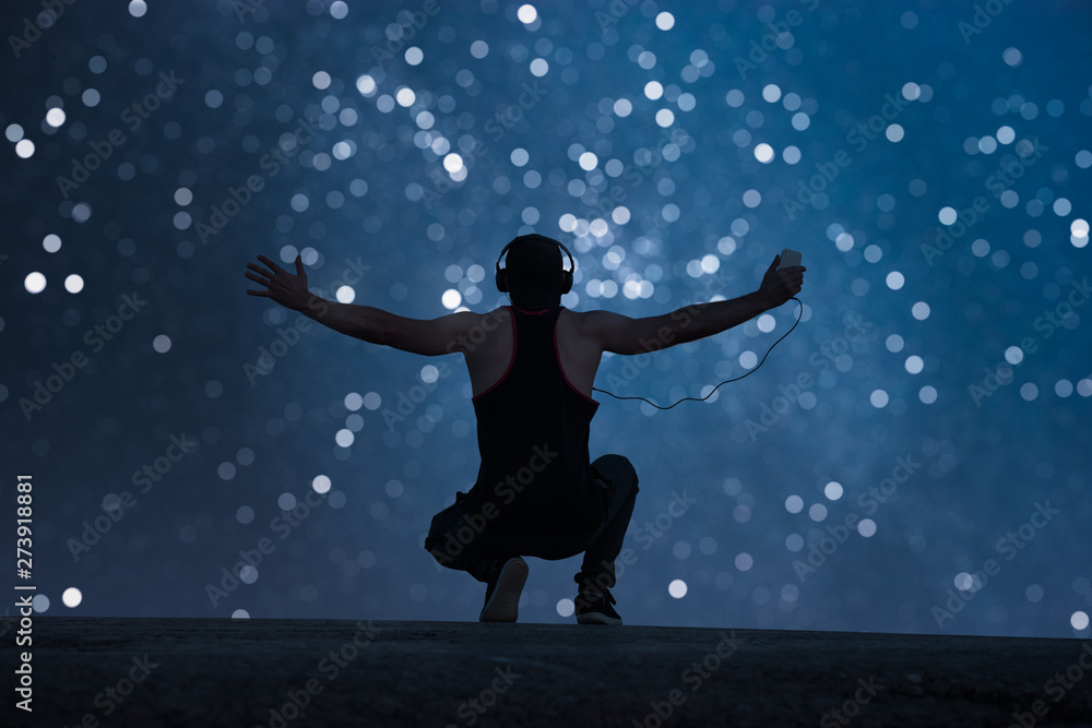 A man with headphones raised his hands up. Starry bokeh background A man with headphones raised his hands up. Starry bokeh background