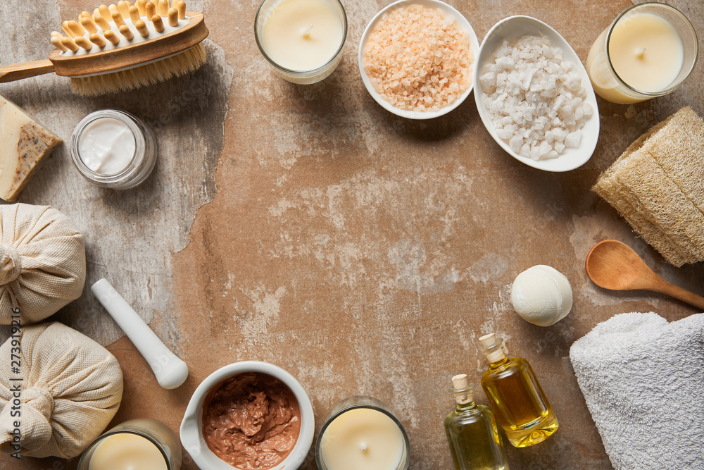 top view of natural cosmetic ingredients and beauty supplies near decorative candles on textured weathered beige surface top view of natural cosmetic ingredients and beauty supplies near decorative candles on textured weathered beige surface