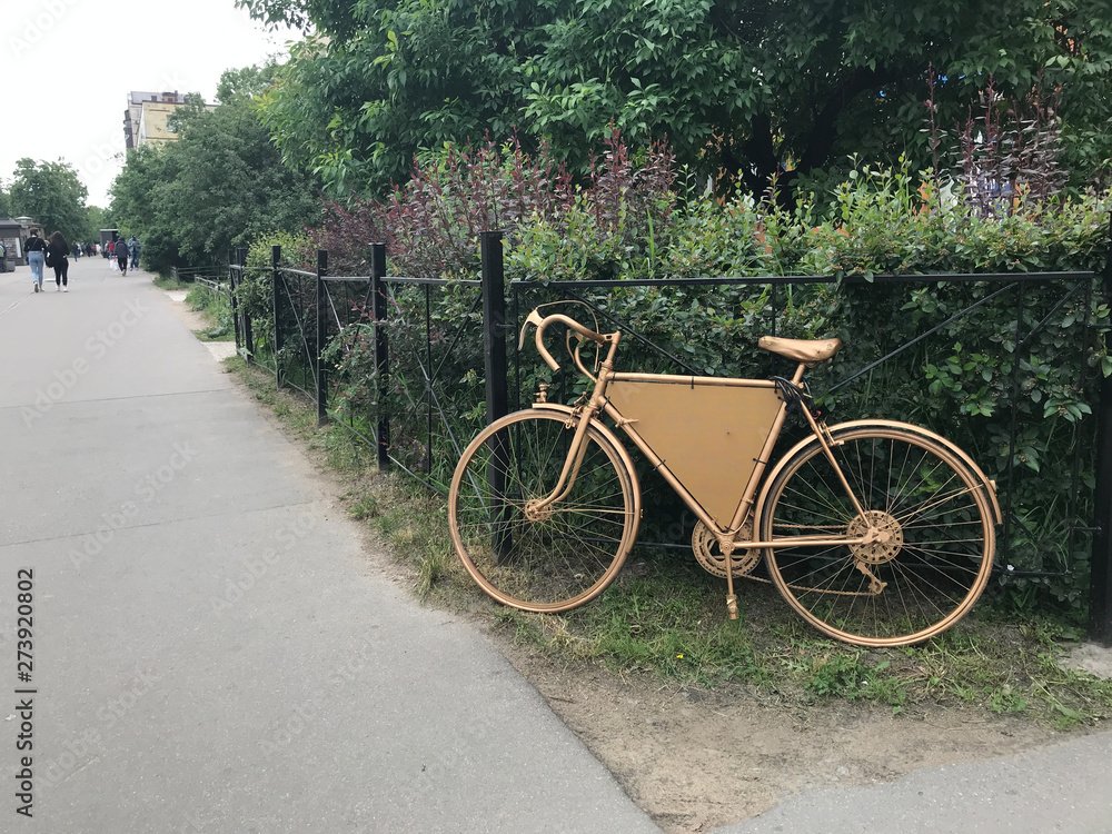 Golden retro bike in front of bushes