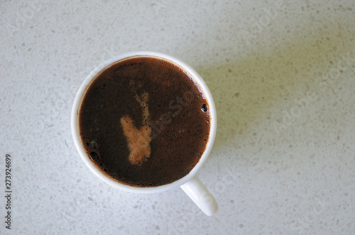 A cup of coffee with froth on a light background. View from above. Space for text and advertising.