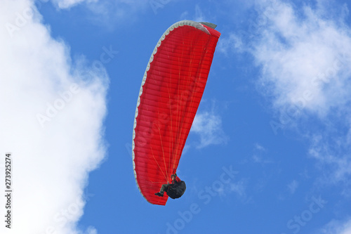 Paraglider flying red wing