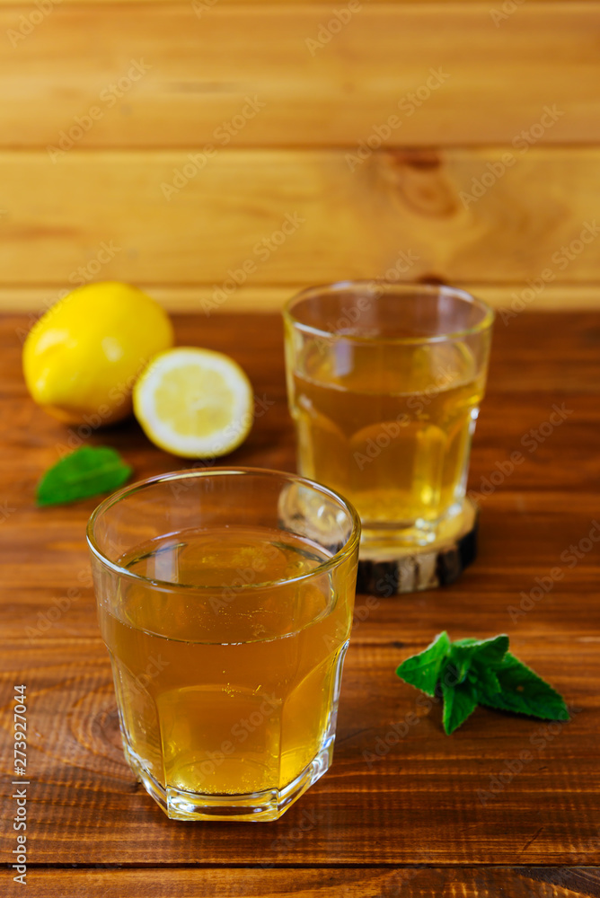 Kombucha tea with lemon, ice and mint on a wooden table. Probiotic food. Kombucha tea with lemon, ice and mint on a wooden table. Probiotic food.