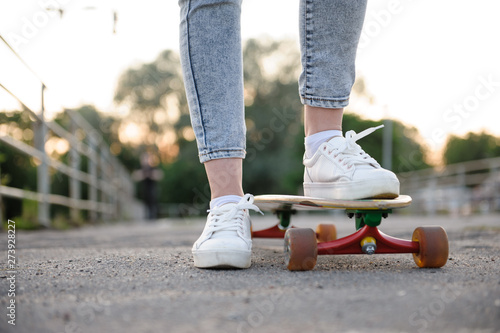 Girl with longboard wearing sneakers shoes in urban style