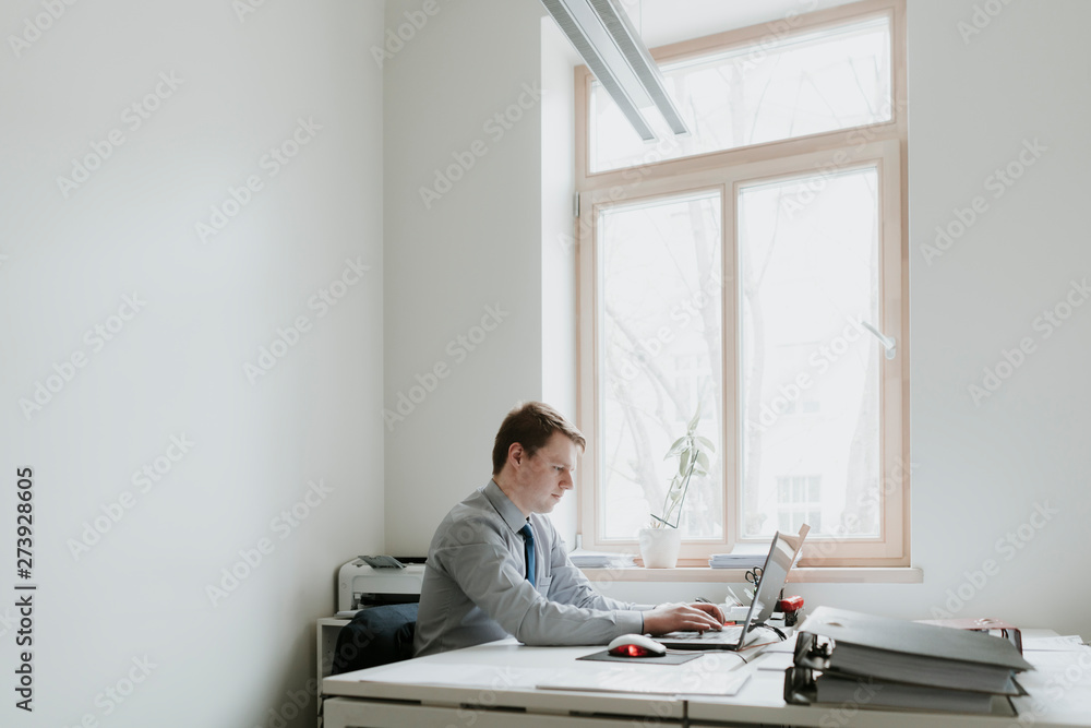 Young businessman using laptop at desk in office Young businessman using laptop at desk in office