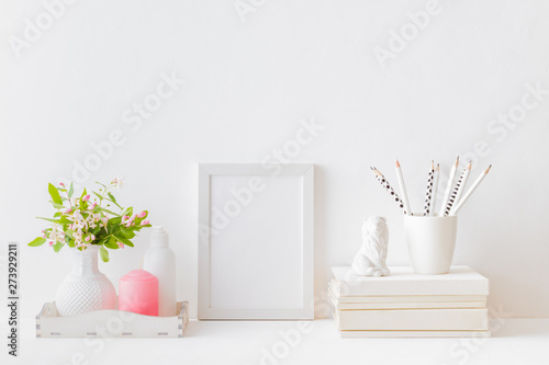 Home interior with decor elements. White frame  branches with green leaves in a vase  interior decoration