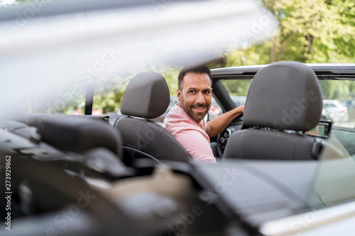 Man sitting in car with closing convertible top © Westend61