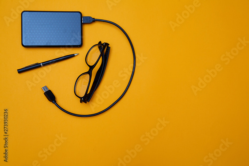 Blogging, blog and blogger or social media concept: glasses and an external hard drive on a yellow background. Flat lay