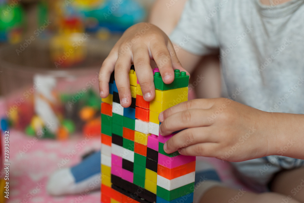 Small hands of the child collects the bright plastic colored Designer. Educational toys and Early learning Small hands of the child collects the bright plastic colored Designer. Educational toys and Early learning