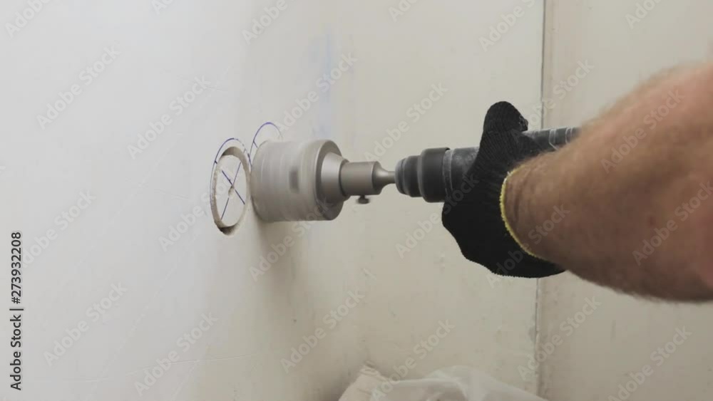 A worker drills a concrete wall with a diamond crown on a perforator - electrical work at home - professional tips on a power tool