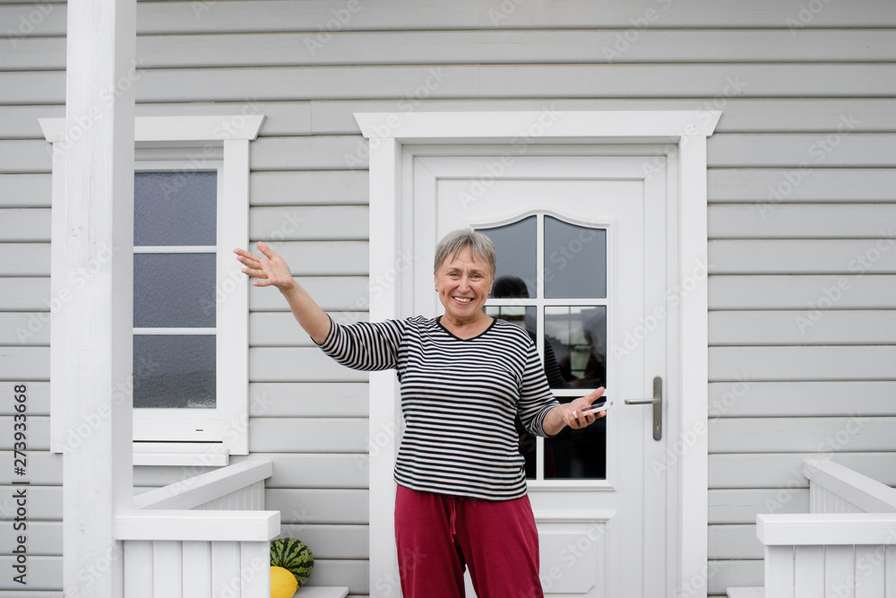 Happy senior woman standing on porch of her house Happy senior woman standing on porch of her house