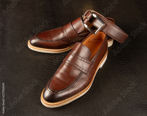 Men's shoes and brown belt against the background of python skin